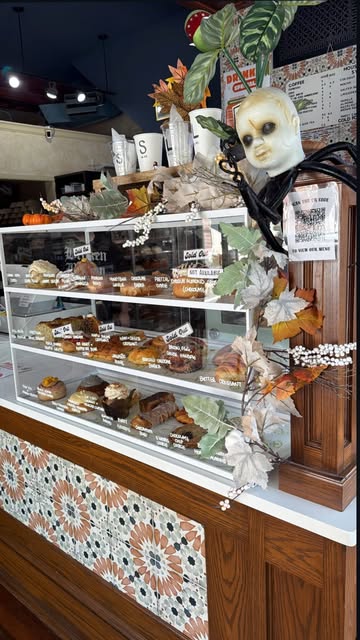 The bakehouse pastry case decorated with plants, autumn leaves, and a little skull