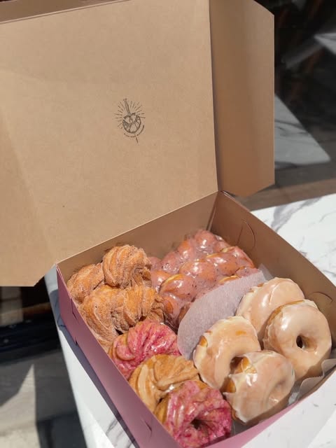 An open Black Magic Bakehouse box filled with glazed and sugar-coated pastries